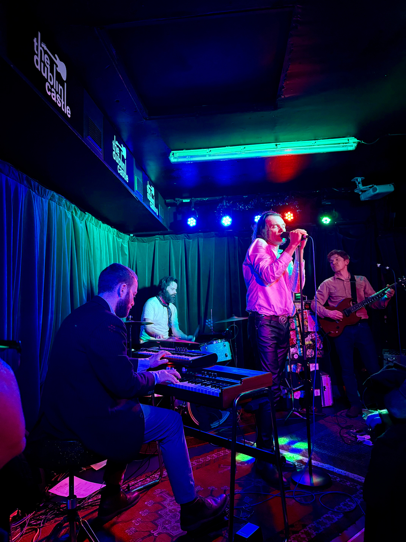Auto-generated description: A band is performing live on stage with a singer and musicians playing various instruments.